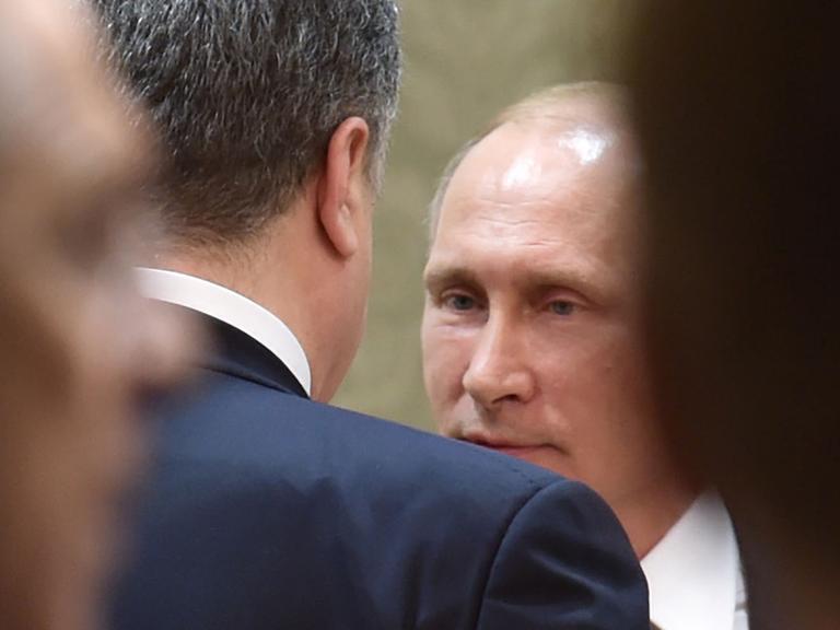 Der russische Präsident Wladimir Putin (hinten) spricht während des Minsker Ukraine-Gipfels mit dem ukrainischen Staatschef Petro Poroschenko.