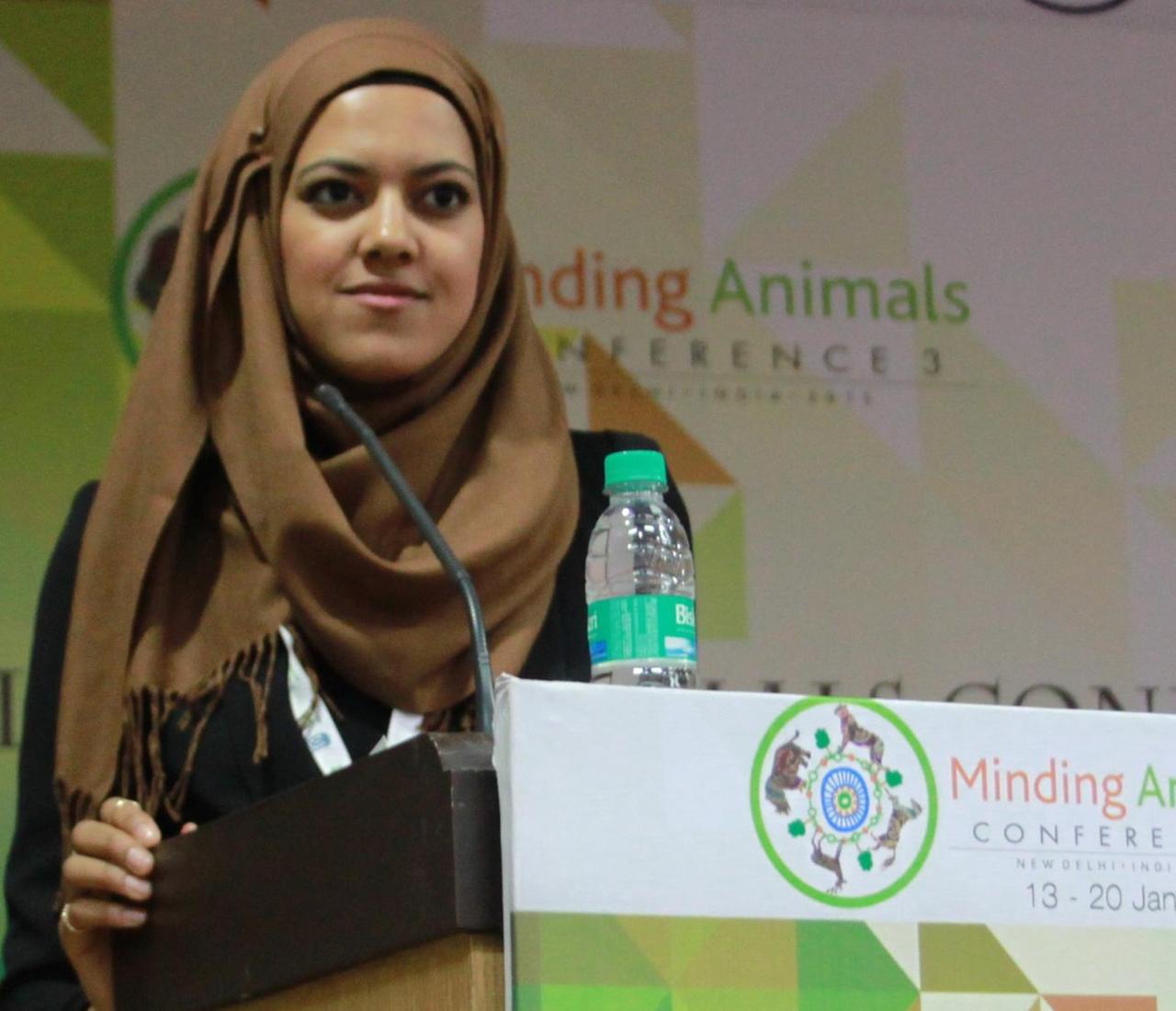 El Maaroufi am Rednerpult mit Werbung für eine Konferenz zum Thema "Minding Animals" im Hintergrund.
