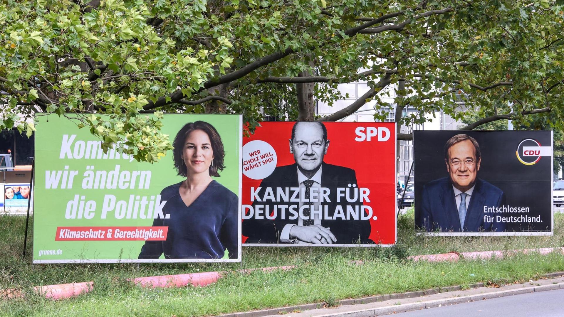 Plakate der Kanzlerkandidaten Annalena Baerbock (B90/Grüne), Olaf Scholz (SPD) und Armin Laschet (CDU) stehen nebeneinander auf einer Strasse in Berlin kurz vor den Bundestagswahlen.