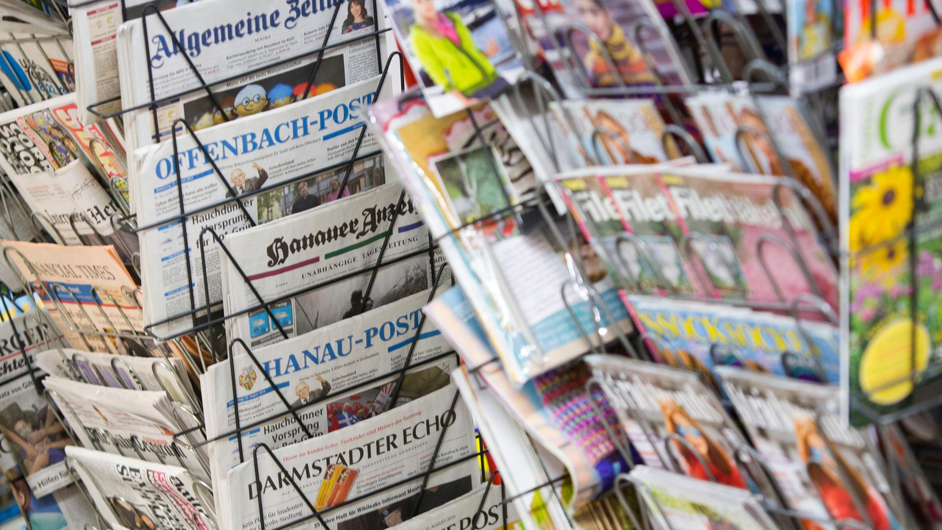 Tageszeitungen stecken an einem Zeitungsstand in Drehständern. Tageszeitungen stecken an einem Zeitungsstand in Drehständern.