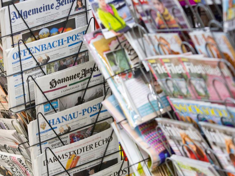 Tageszeitungen stecken an einem Zeitungsstand in Drehständern.