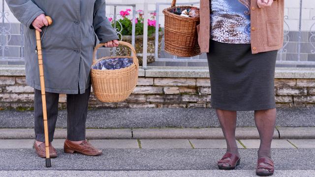Zwei ältere Dame tragen nach einem Einkauf ihre Lebensmittel nach Hause.
