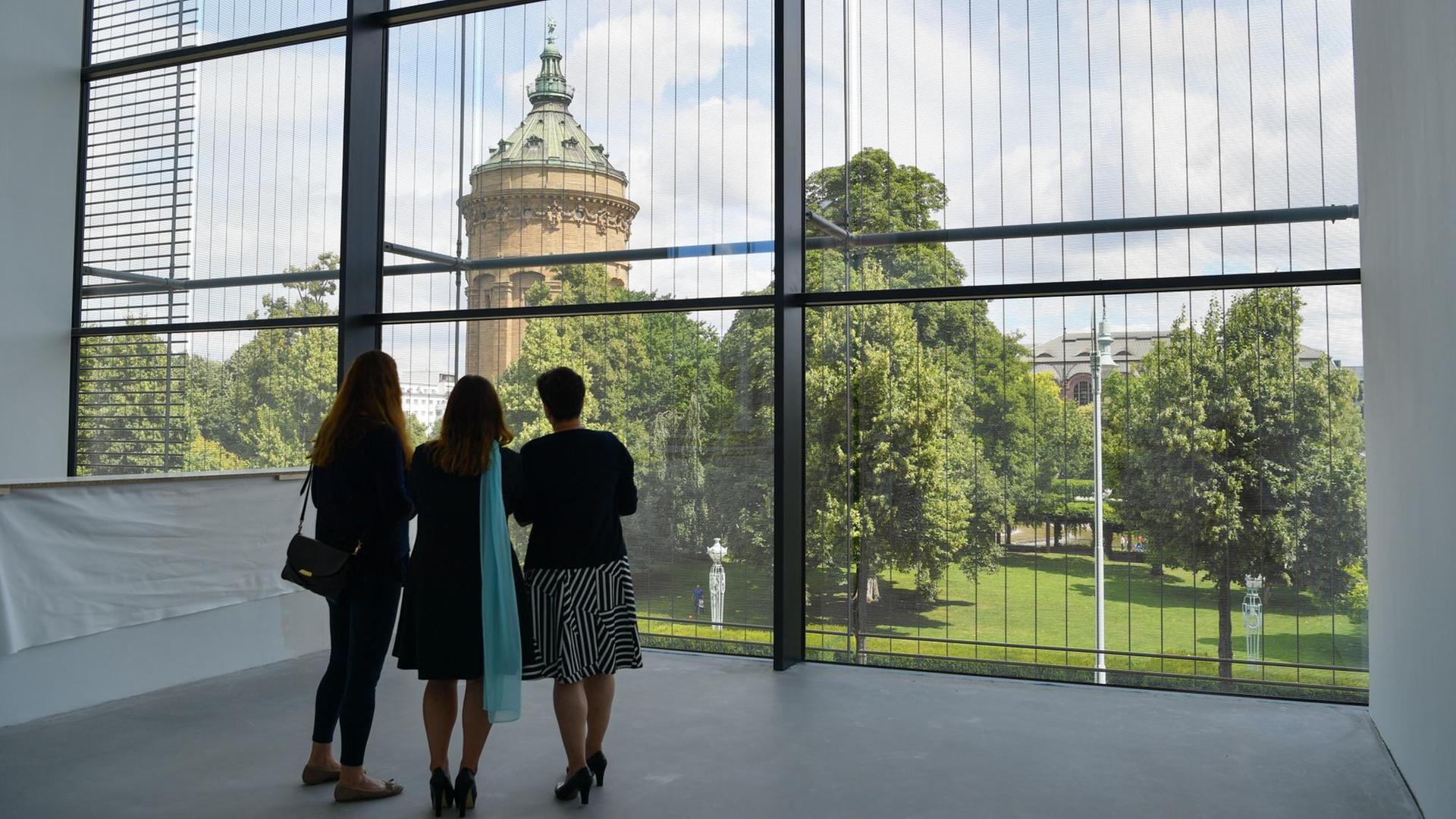 Besucher betrachten am 15.07.2017 in Mannheim durch ein Panoramafenster des Neubaus der Kunsthalle den Mannheimer Wasserturm. Besucher betrachten am 15.07.2017 in Mannheim durch ein Panoramafenster des Neubaus der Kunsthalle den Mannheimer Wasserturm.