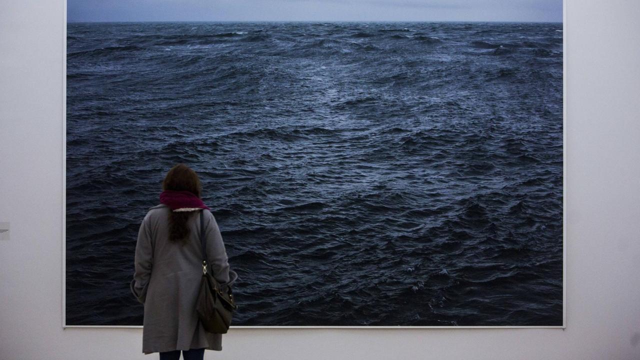 Ausstellungsbesucherin vor einem Werk des Fotografen Wolfgang Tillmans, auf dem das Meer zu sehen ist Ausstellungsbesucherin vor einem Werk des Fotografen Wolfgang Tillmans, auf dem das Meer zu sehen ist
