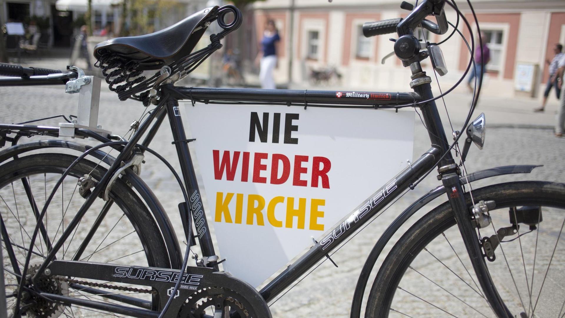 Ein Fahrrad mit der Aufschrift "Nie wieder Kirche" in Schwarz-Rot-Gold