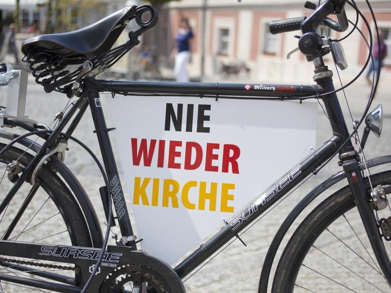 Ein Fahrrad mit der Aufschrift "Nie wieder Kirche" in Schwarz-Rot-Gold