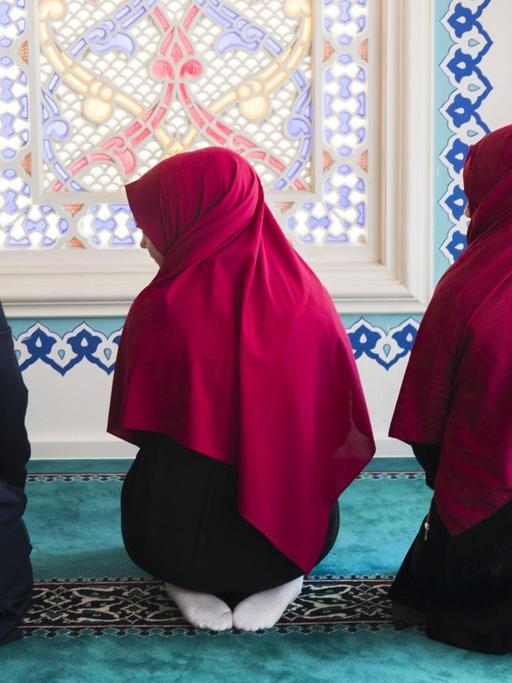 Drei junge Frauen beten in der Sehitlik Moschee in Berlin Neukölln, 2017.