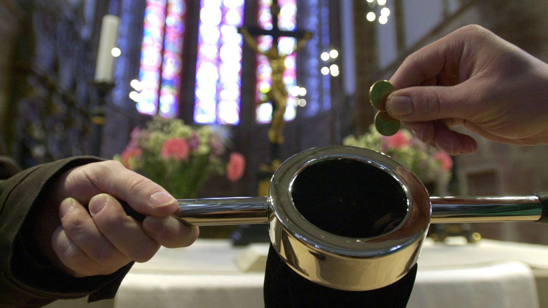 Ein Besucher der Saarbrücker Stiftskirche steckt einige Münzen in den Klingelbeutel. Ein Besucher der Saarbrücker Stiftskirche steckt einige Münzen in den Klingelbeutel.
