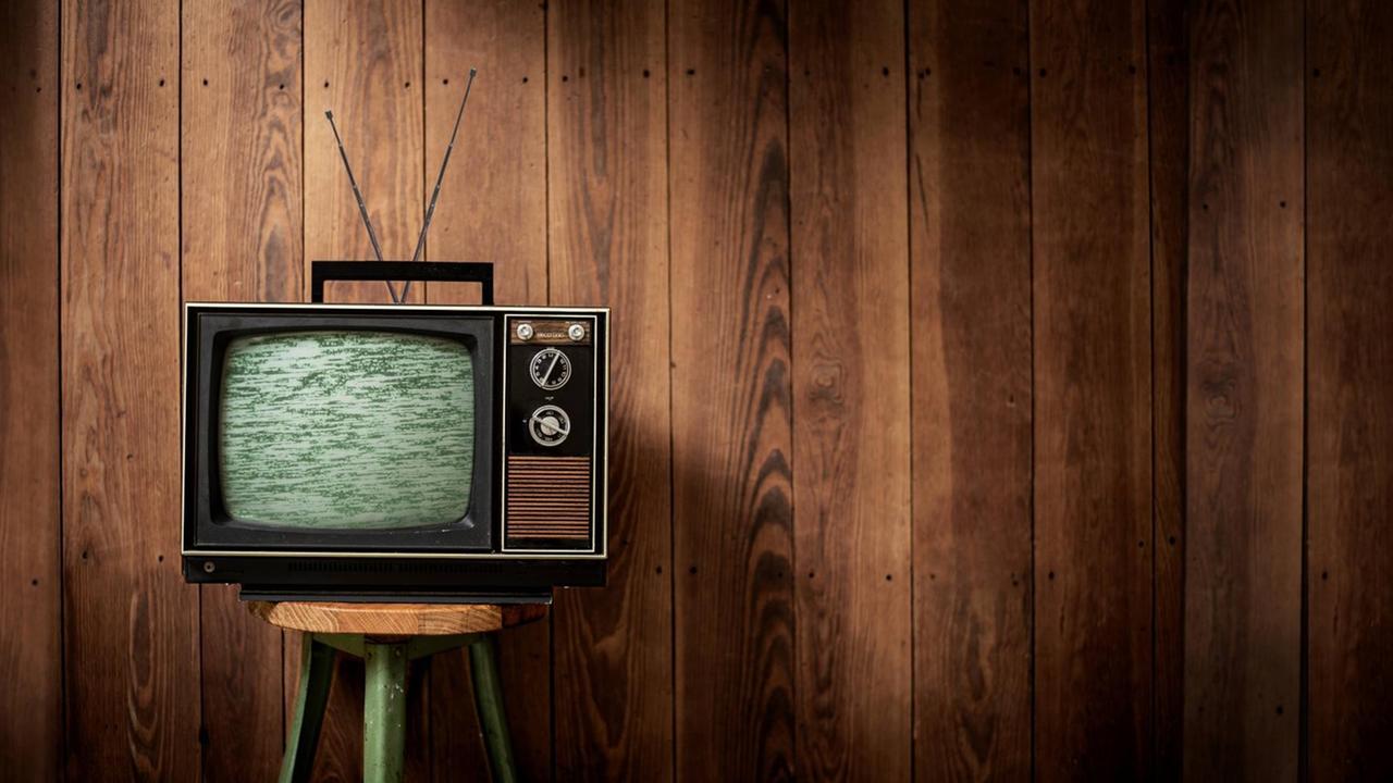 Ein alter Fernseher vor einer Holzwand. Ein alter Fernseher vor einer Holzwand.