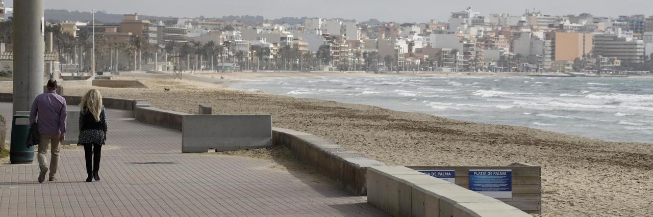 Ein Mann und eine Frau gehen über die Promenade am Strand von Arenal. Ein Mann und eine Frau gehen über die Promenade am Strand von Arenal.