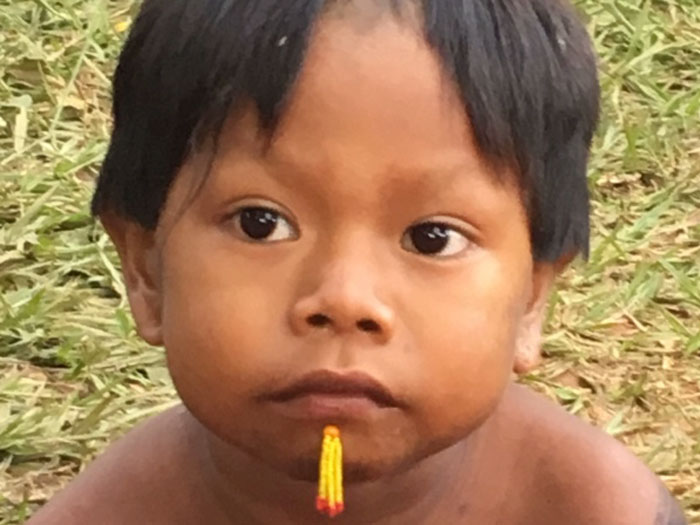 Indigenes Kind des Kayapó Stammes. Das Kind ist zwischen 2 und 4 Jahren alt und hat am Kinn einen gelben Streifen