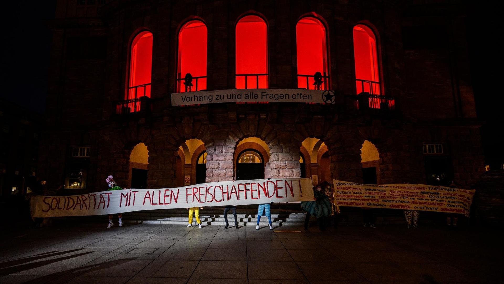 Die Künstler des Staatstheaters stehen mit einem Banner „Solidarität mit allen Freischaffenden!“ vor dem Haus.
