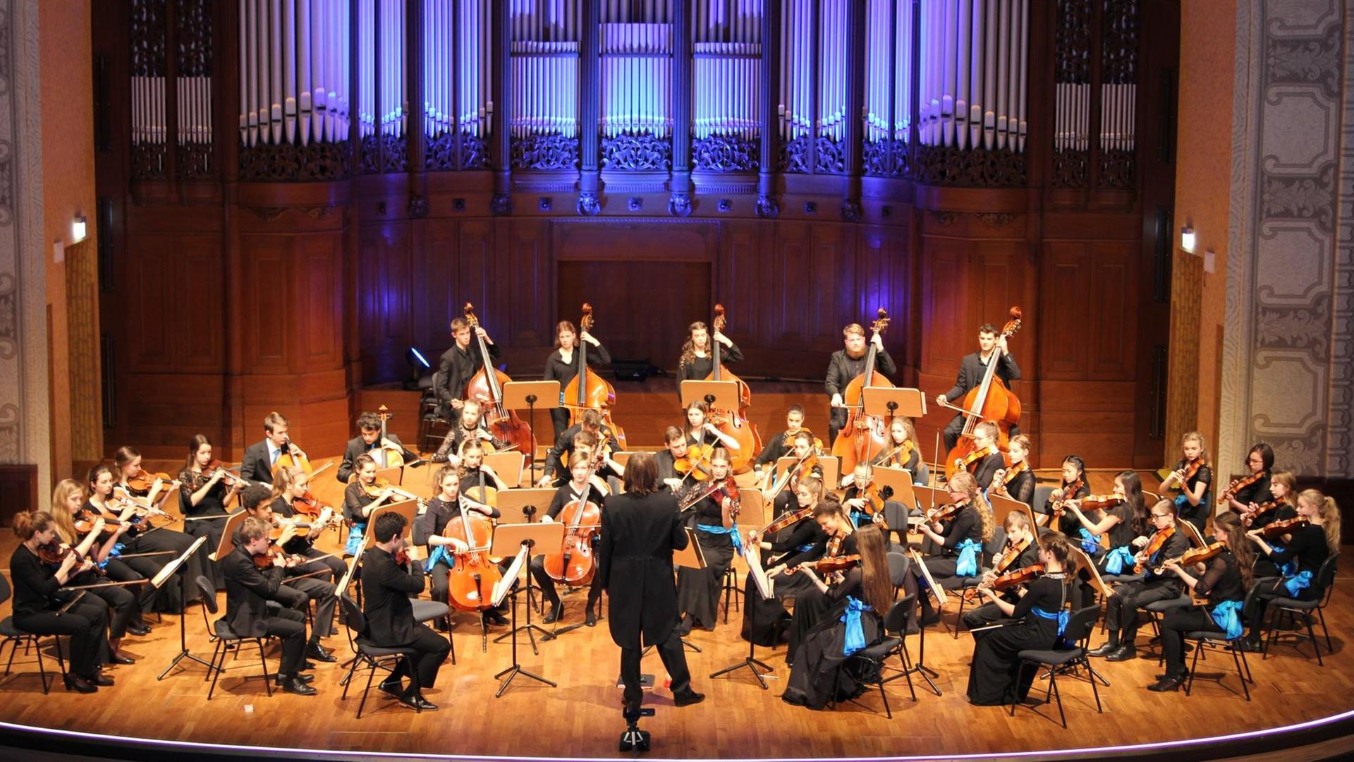 Das Orchester sitzt auf einer festlich beleuchteten, großen Bühne. Das Orchester sitzt auf einer festlich beleuchteten, großen Bühne.