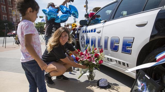 Eine Frau und ihre Tochter legen in Dallas Blumen an einem Polizeiauto nieder, um der getöteten Polizisten zu gedenken