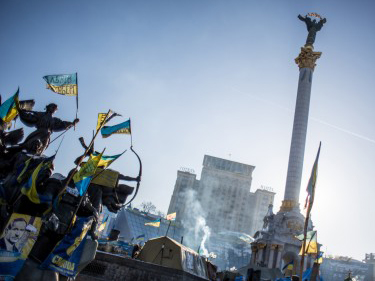 Proteste auf dem Unabhängigkeitsplatz in Kiew. Menschen schwingen Fahnen.