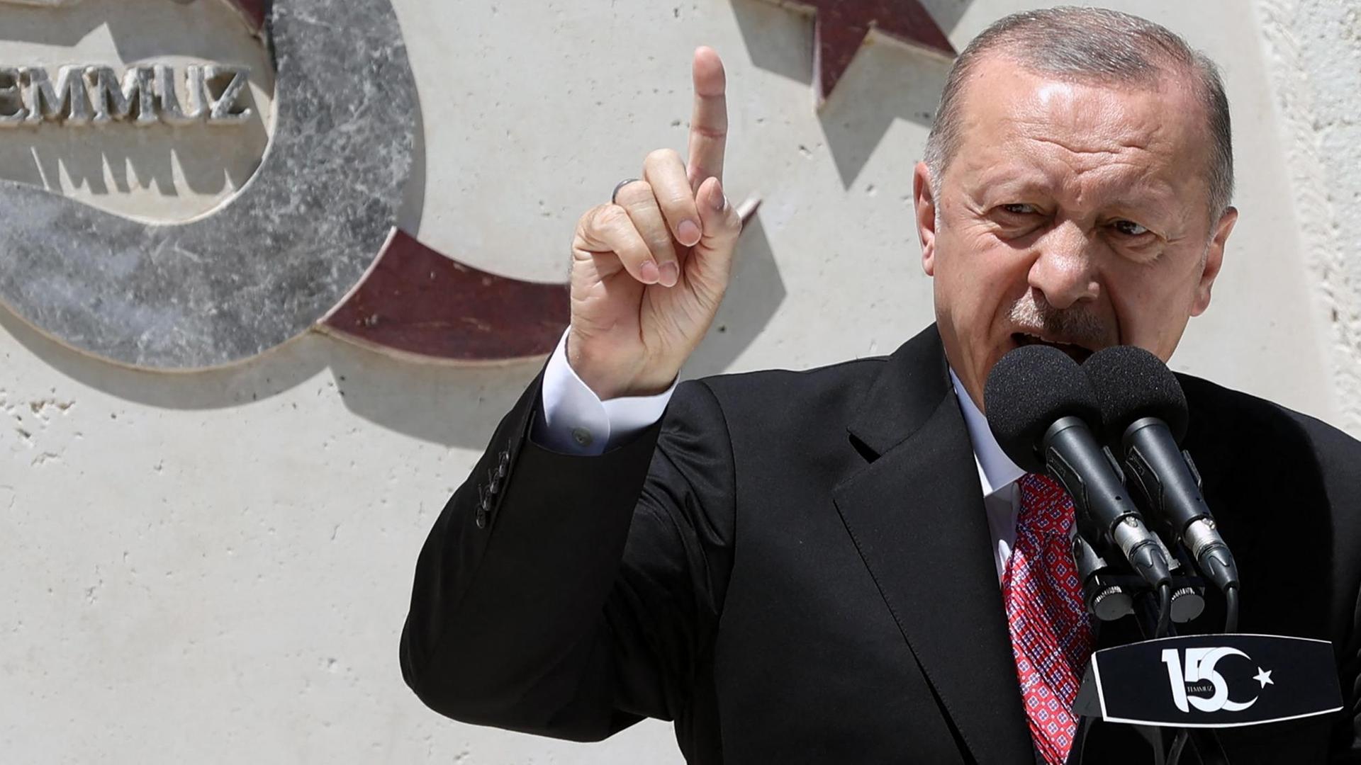 Der türkische Präsident Erdogan steht an einem Mikrofon und spricht aufgeregt.