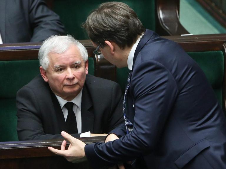 Jaroslaw Kaczynski sitzt auf einer Abgeordnetenbank, Zbigniew Ziobro redet auf ihn ein.