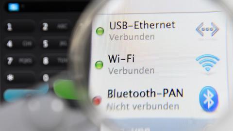 ILLUSTRATION - Eine Lupe ist am 20.07.2015 in Frankfurt am Main (Hessen) auf einen Computer-Bildschirm gerichtet, auf dem USB-Ethernet-. Wi-Fi- und Bluetooth-Verbindungen angezeigt sind. Foto: Arne Dedert/dpa | Verwendung weltweit