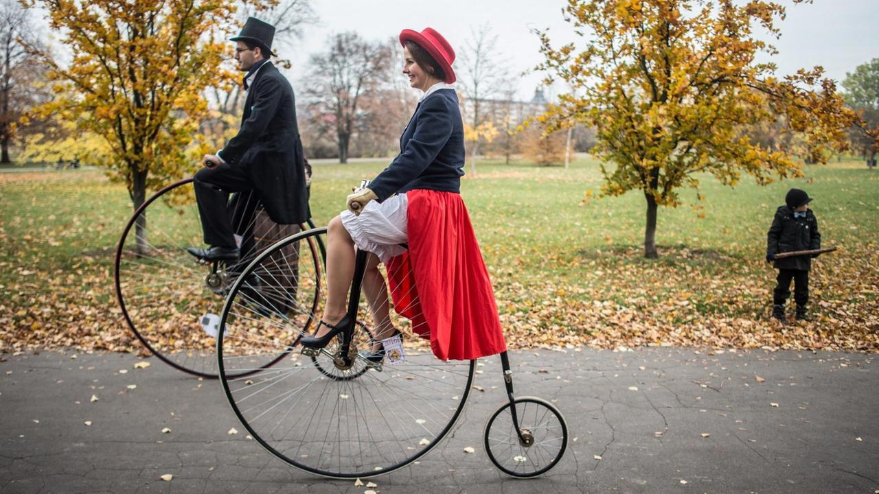 Zwei historisch gekleidete Teilnehmer des Ein-Meilen-Rennens auf Hochrädern, historischen Fahrrädern mit riesigen Vorderrädern, am 5. November 2016 im Letna-Park in Prag.