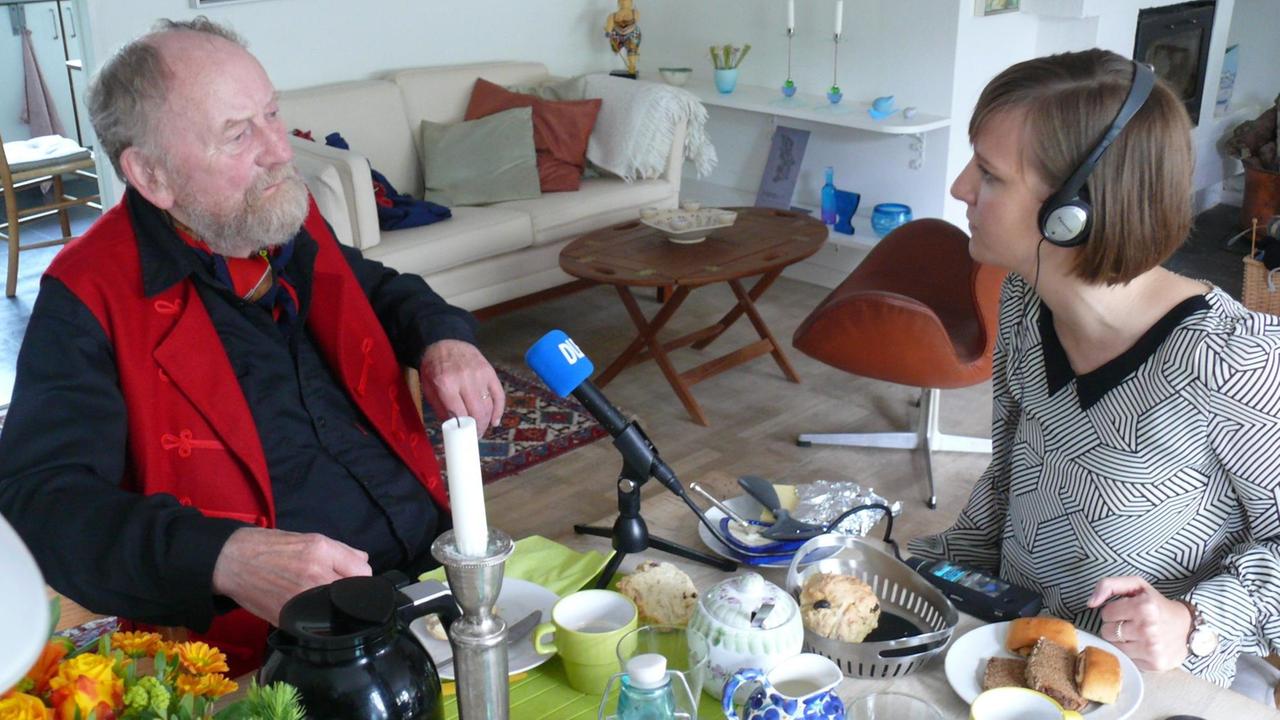 Der Karikaturist Kurt Westergaard wird an seinem Wohnzimmertisch von Deutschlandfunk-Nachrichtenredakteurin Jana Sinram interviewt. Der Karikaturist Kurt Westergaard wird an seinem Wohnzimmertisch von Deutschlandfunk-Nachrichtenredakteurin Jana Sinram interviewt.