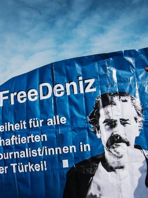 Zwei Demonstranten halten ein Plakat hoch, um für die Freilassung des in der Türkei inhaftierten Journalisten Deniz Yücel zu werben.
