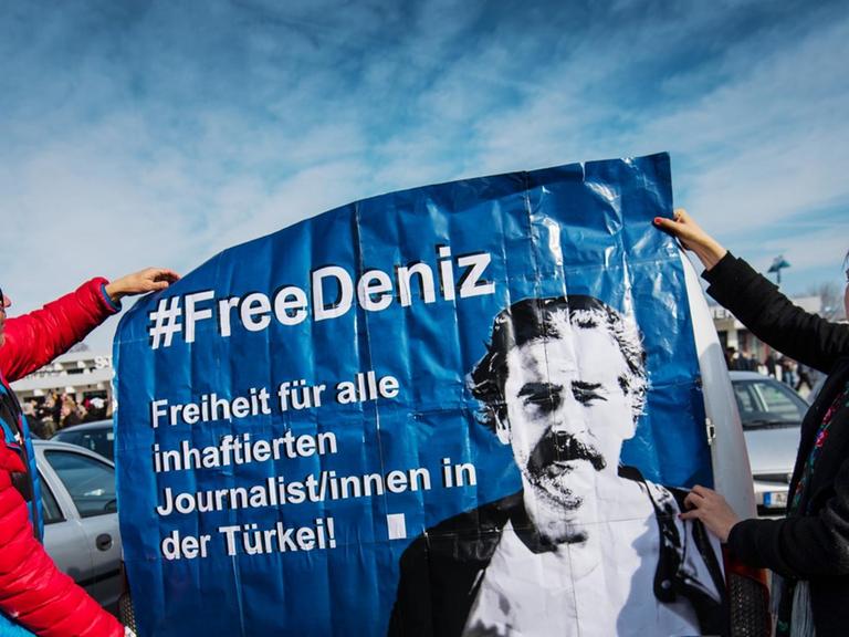 Zwei Demonstranten halten ein Plakat hoch, um für die Freilassung des in der Türkei inhaftierten Journalisten Deniz Yücel zu werben.