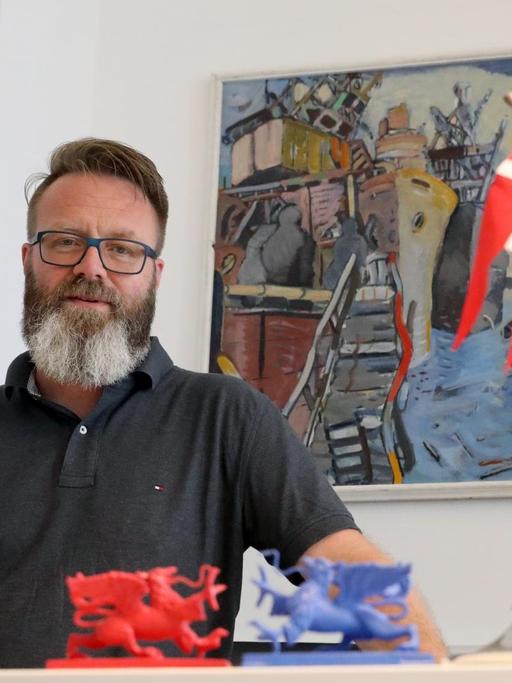 Der Däne Claus Ruhe Madsen, Oberbürgermeister von Rostock, sitzt an seinem Schreibtisch hinter einer dänischen Fahne.