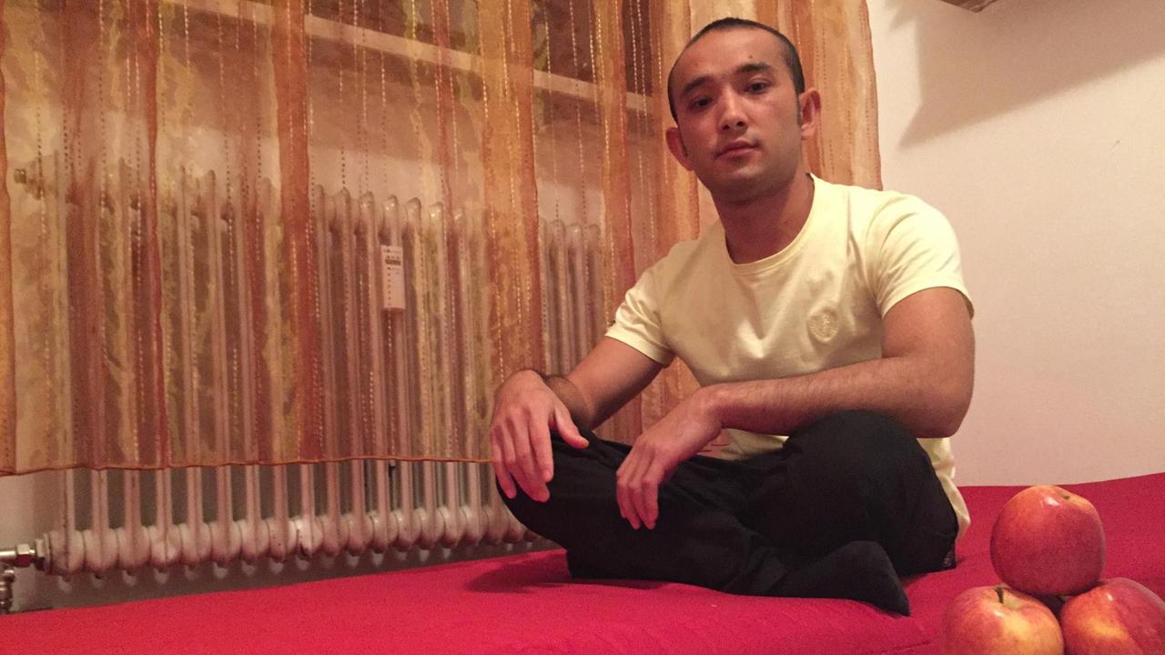 Amruddin Muradi sitzt in einer Wohnung auf einer Matratze.