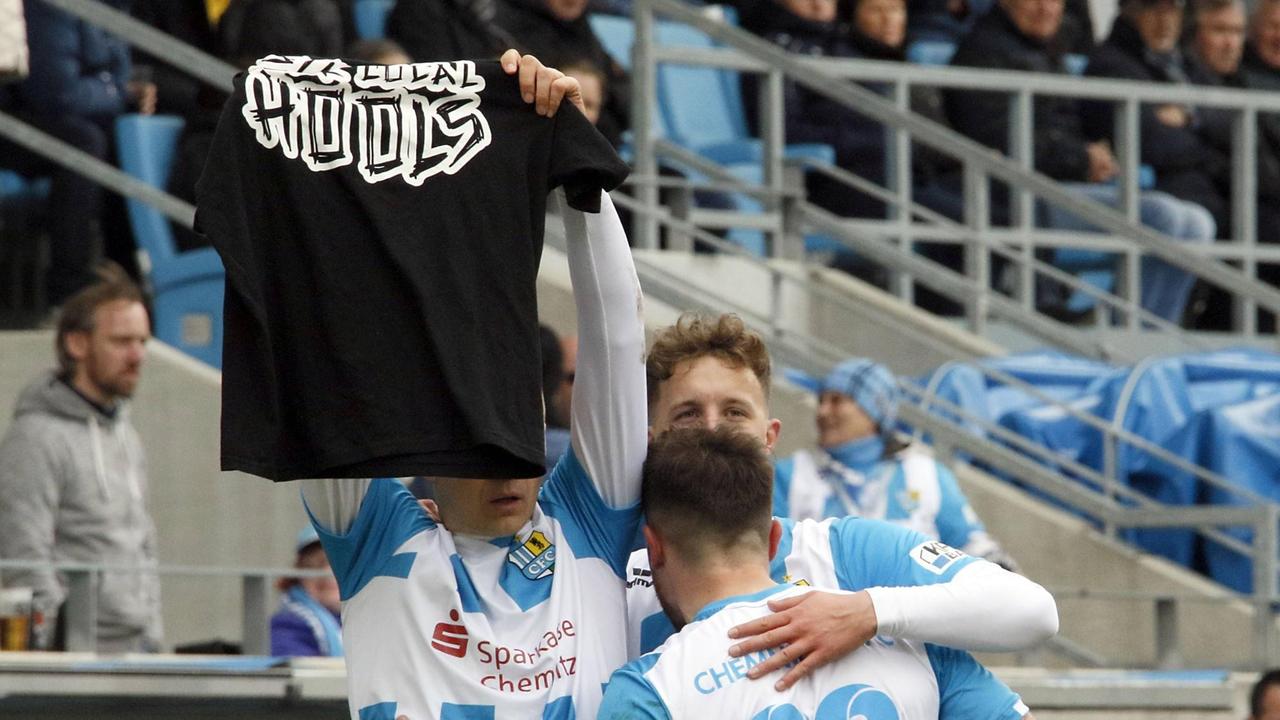 Daniel Frahn und zwei weitere Teamkollegen umarmen sich während Frahn eine Hooligan-Trikot in die Luft hält. Daniel Frahn und zwei weitere Teamkollegen umarmen sich während Frahn eine Hooligan-Trikot in die Luft hält.
