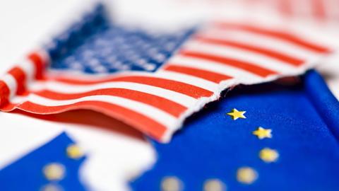 Gerissene Fahnen von den USA und EU, Symbolfoto für drohenden Handelskrieg