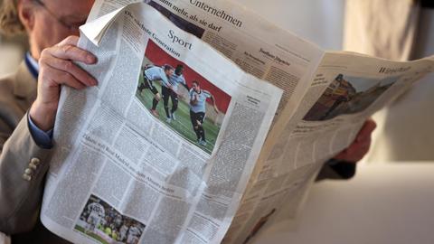 Ein Teilnehmer liest am 06.06.2013 in Köln (Nordrhein-Westfalen) auf dem Medienforum in Köln eine Tageszeitung.