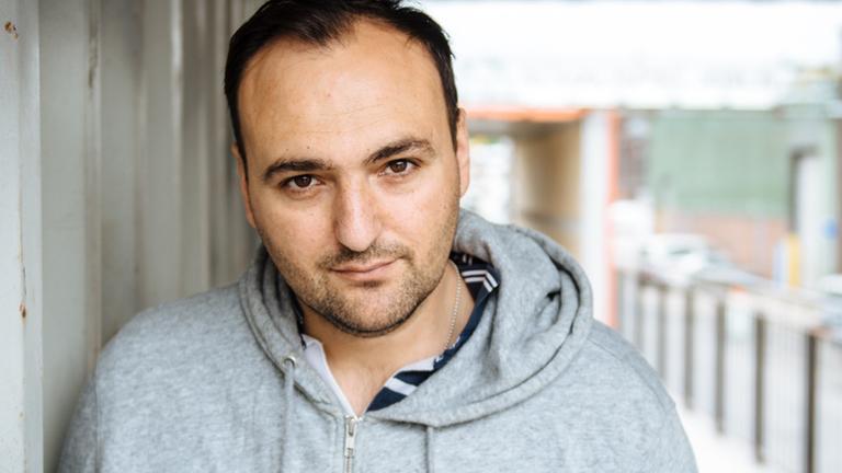Nuran David Calis trägt legere Kleidung und blickt in die Kamera. Nuran David Calis trägt legere Kleidung und blickt in die Kamera.