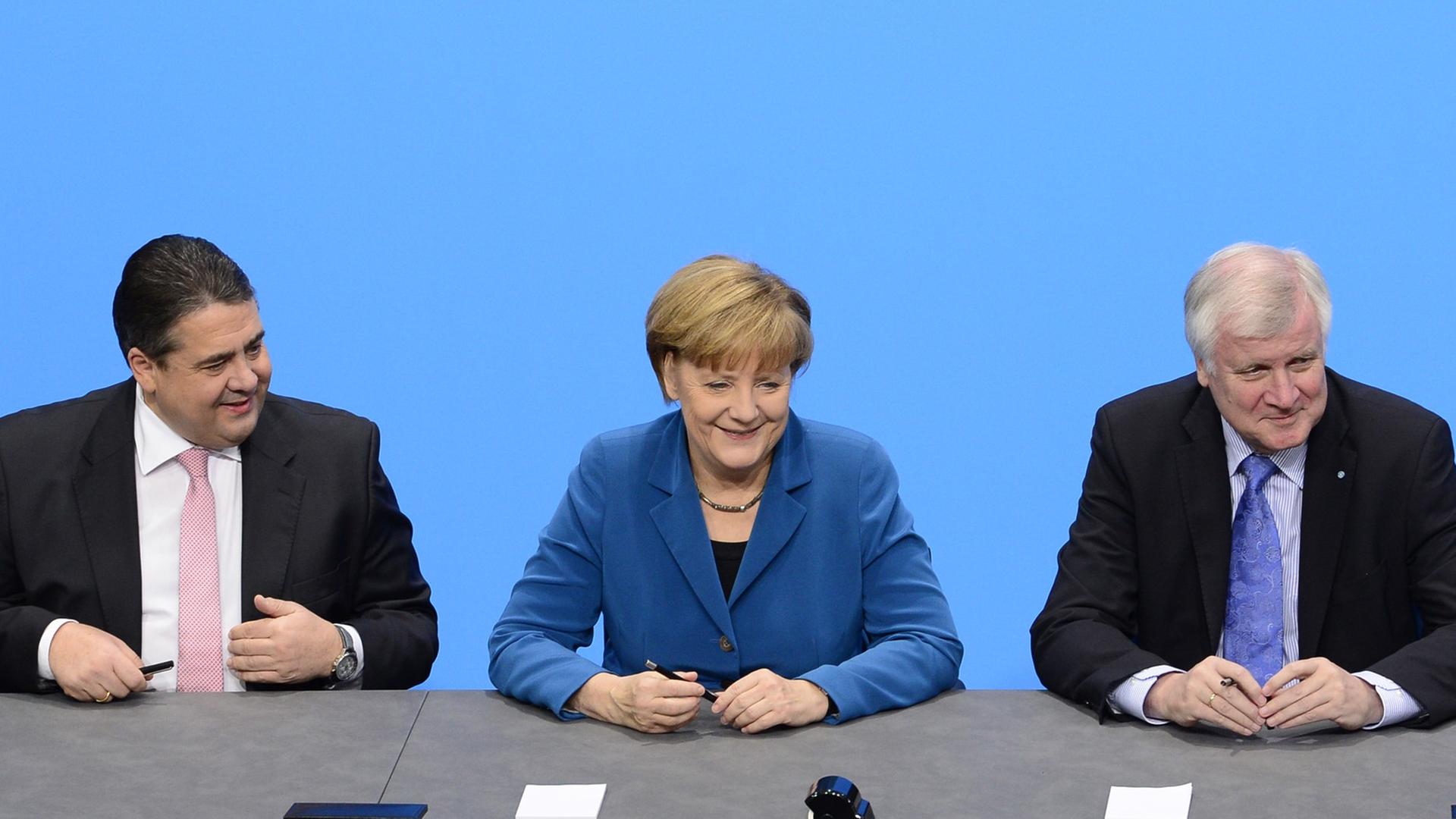 Der SPD-Vorsitzende Sigmar Gabriel, Bundeskanzlerin Angela Merkel (CDU) und CSU-Chef Horst Seehofer sitzen an einem Tisch und unterzeichnen den Koalitionsvertrag. Der SPD-Vorsitzende Sigmar Gabriel, Bundeskanzlerin Angela Merkel (CDU) und CSU-Chef Horst Seehofer sitzen an einem Tisch und unterzeichnen den Koalitionsvertrag.