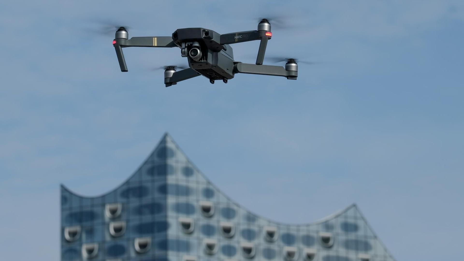 Eine Drohne (Typ Quadrocopter), die mit einer Foto/Videokamera ausgestattet ist, schwebt am 12.03.2017 in Hamburg in der Nähe der Elbphilharmonie am Himmel. Die Nutzung von Drohnen, sogenannten unbemannten Luftfahrtsystemen (UAS), ist im Luftverkehrsgesetz geregelt.