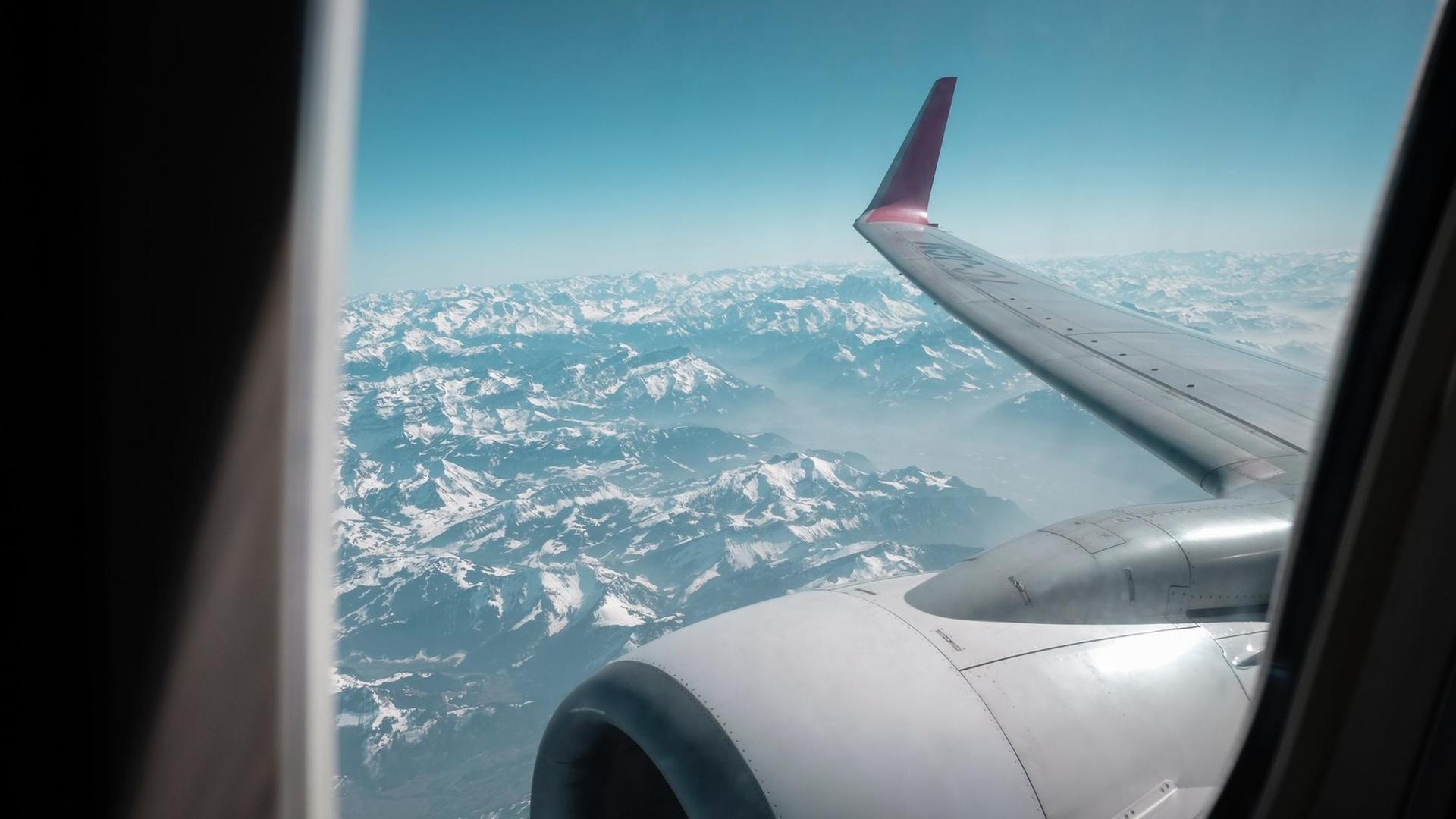 Wenn einen nur das Flugzeug zu seinem Liebsten bringt. Die Distanzen zwischen Liebespaaren werden immer größer. Zu sehen: Blick aus einem Flugzeugfenster auf eine Gebirgslandschaft. Wenn einen nur das Flugzeug zu seinem Liebsten bringt. Die Distanzen zwischen Liebespaaren werden immer größer. Zu sehen: Blick aus einem Flugzeugfenster auf eine Gebirgslandschaft.