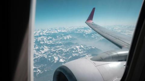 Blick aus einem Flugzeugfenster auf eine Gebirgslandschaft.