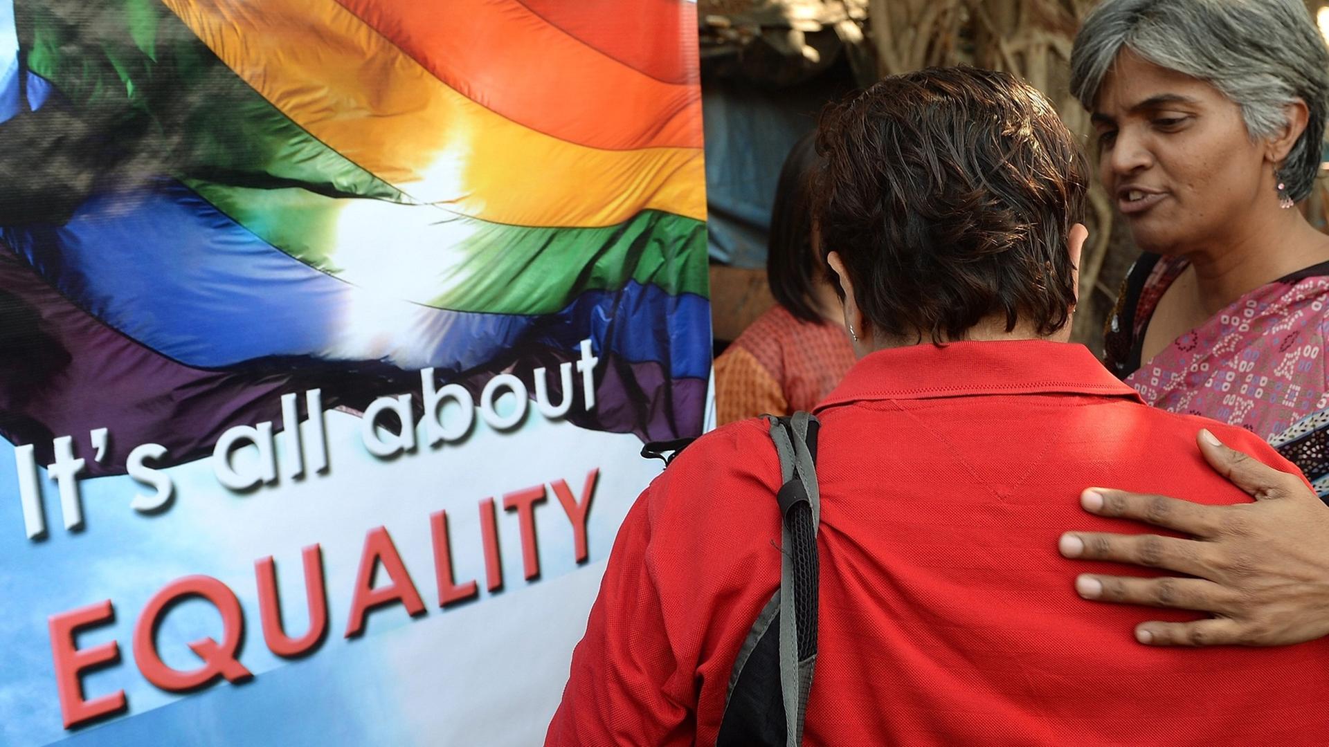 Vor einem Plakat mit einer Regenbogenflagge, dem Symbol für die Schwulen- und Lesbenbewegung, mit der Aufschrift "It's all about Equality" stehen zwei Frauen, eine davon mit dem Rücken zur Kamera, und betrachten es. Aufgenommen wurde das Bild bei einer Demonstranten für die Rechte Homosexueller in Mumbai am 11. Dezember 2013. Vor einem Plakat mit einer Regenbogenflagge, dem Symbol für die Schwulen- und Lesbenbewegung, mit der Aufschrift "It's all about Equality" stehen zwei Frauen, eine davon mit dem Rücken zur Kamera, und betrachten es. Aufgenommen wurde das Bild bei einer Demonstranten für die Rechte Homosexueller in Mumbai am 11. Dezember 2013.