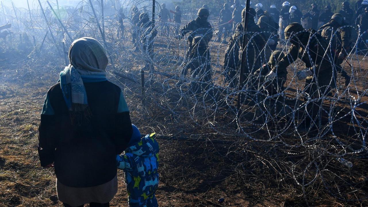 6692098 09.11.2021 A woman with a child walks along the barbed wire fence in an illegal migrant camp on the Belarusian-Polish border in Grodno region, Belarus. Hundreds if not thousands of migrants from the Middle East and North Africa tried to storm the border from Belarus into Poland, cutting razor wire defenses and using branches to try and climb over fences. Polish authorities regarded this as "the largest attempt of mass forceful penetration" and strengthened border security. Viktor Tolochko / Sputnik 6692098 09.11.2021 A woman with a child walks along the barbed wire fence in an illegal migrant camp on the Belarusian-Polish border in Grodno region, Belarus. Hundreds if not thousands of migrants from the Middle East and North Africa tried to storm the border from Belarus into Poland, cutting razor wire defenses and using branches to try and climb over fences. Polish authorities regarded this as "the largest attempt of mass forceful penetration" and strengthened border security. Viktor Tolochko / Sputnik