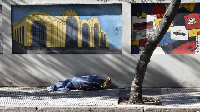 Ein Obdachloser liegt in Bueons Aires in einer Decke auf der Straße