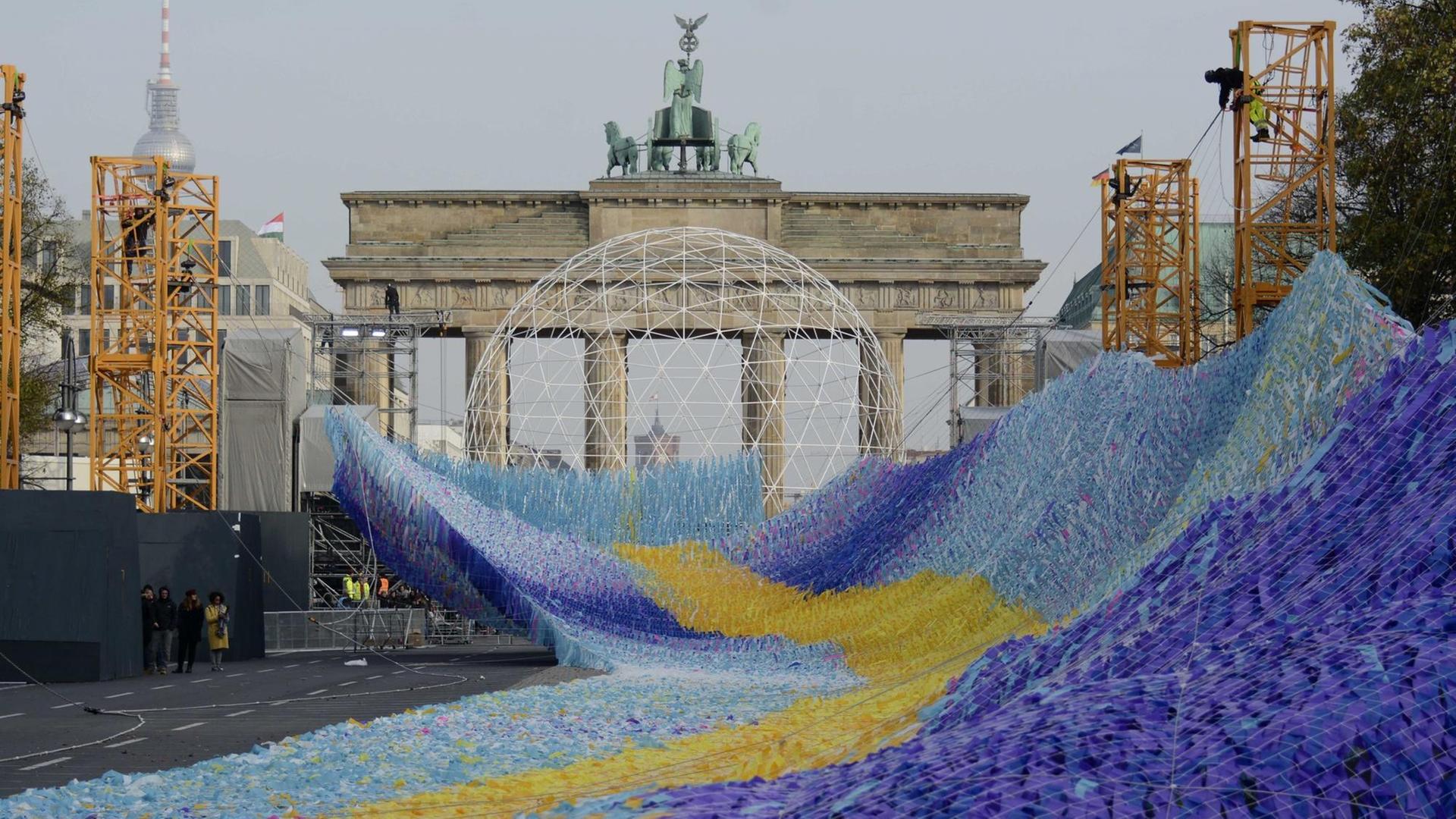 Die Installation "Visions in Motion", eine etwa 100 Meter lange Welle aus Plastikfähnchen, befindet sich vor dem Brandenburger Tor im Aufbau.