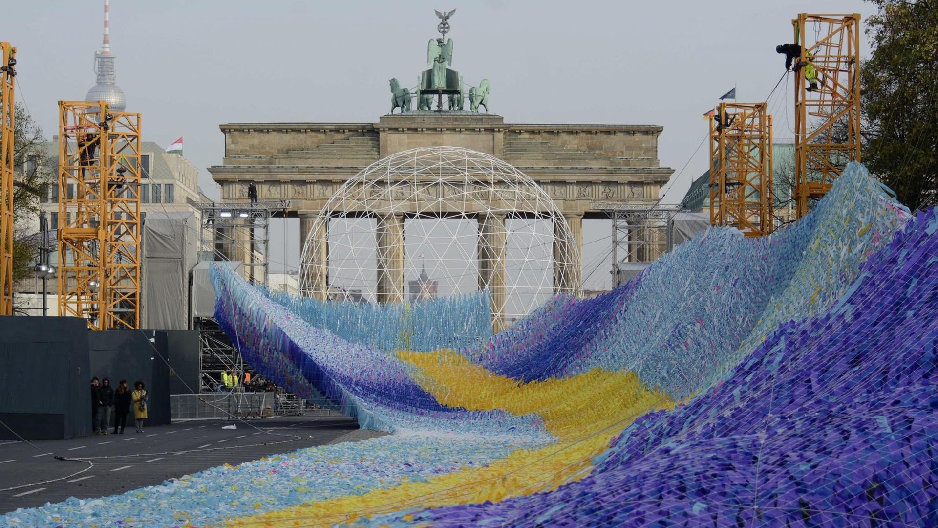 Die Installation "Visions in Motion", eine etwa 100 Meter lange Welle aus Plastikfähnchen, befindet sich vor dem Brandenburger Tor im Aufbau. Die Installation "Visions in Motion", eine etwa 100 Meter lange Welle aus Plastikfähnchen, befindet sich vor dem Brandenburger Tor im Aufbau.