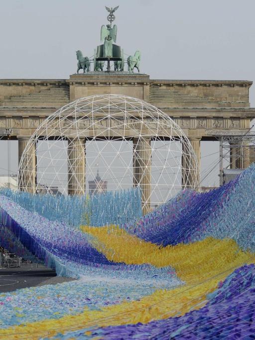 Die Installation "Visions in Motion", eine etwa 100 Meter lange Welle aus Plastikfähnchen, befindet sich vor dem Brandenburger Tor im Aufbau.