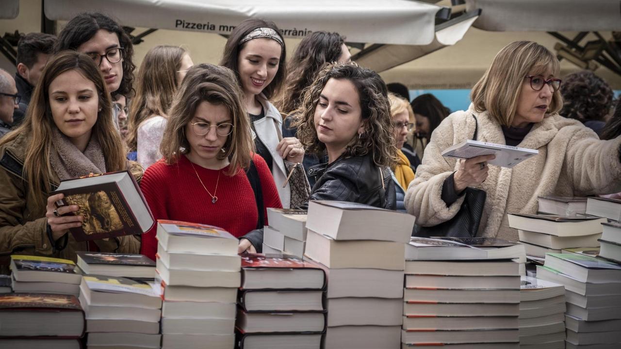 Junge Frauen stehen am Bücherstand und begehen den St. Jordan Tag in Barcelona. Junge Frauen stehen am Bücherstand und begehen den St. Jordan Tag in Barcelona.