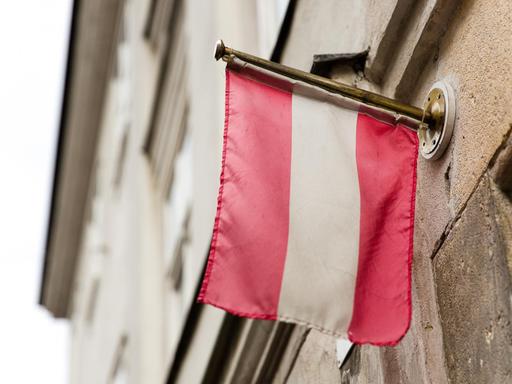 Die Flagge von Österreich hängt an einer Hauswand.