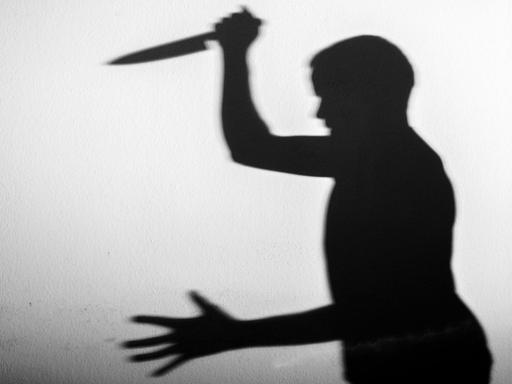 Der Schatten eines Mannes mit einem großen Küchenmesser in der Hand.