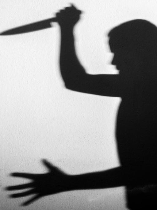 Der Schatten eines Mannes mit einem großen Küchenmesser in der Hand.