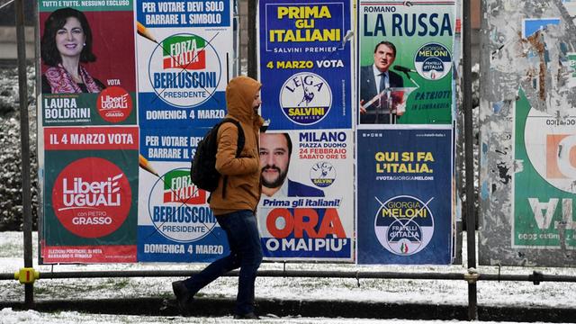 Ein Passant geht an einer Wand mit Wahlplakaten in Mailand vorbei. Italien wählt am 4.3.2018 ein neues Parlament.