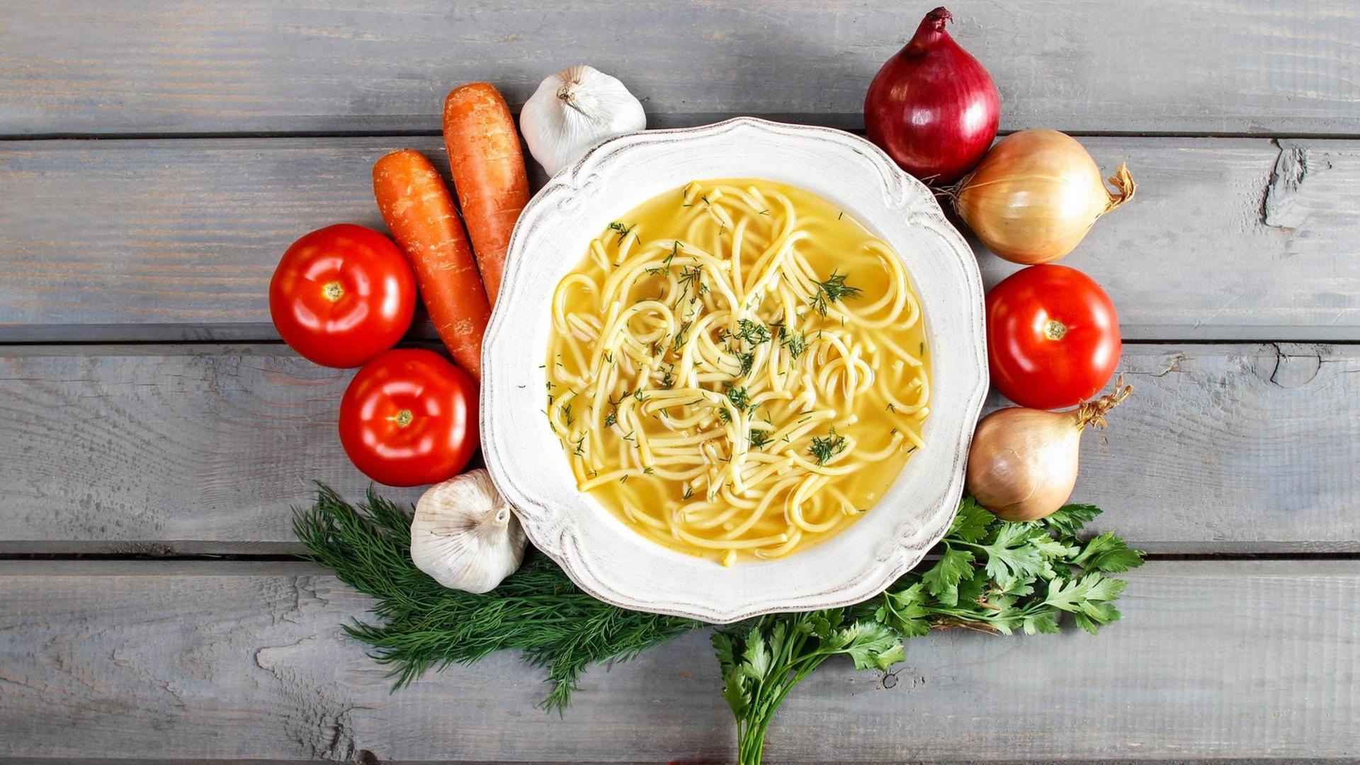 Obst und Gemüse liegen um einen Teller Nudelsuppe. Obst und Gemüse liegen um einen Teller Nudelsuppe.