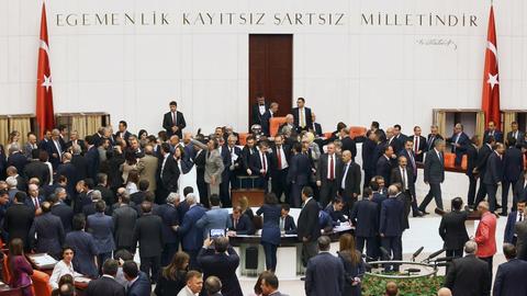 Sie sehen den Parlamentssaal in der türkischen Hauptstadt Ankara, viele Abgeordnete reden dort miteinander.
