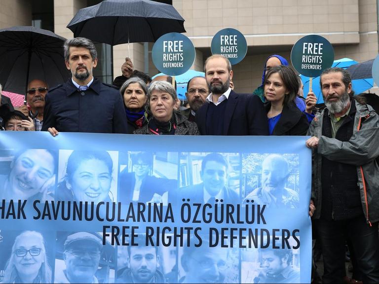 Menschenrechts-Aktivisten demonstrieren am 25.10.2017 vor einem Gericht in Istanbul (Türkei) mit einem Transparent mit Bildern der Angeklagten gegen den Prozess gegen elf Menschenrechtler, darunter auch der Deutsche Peter Steudtner (auf dem Banner der 2.v.r. unten).